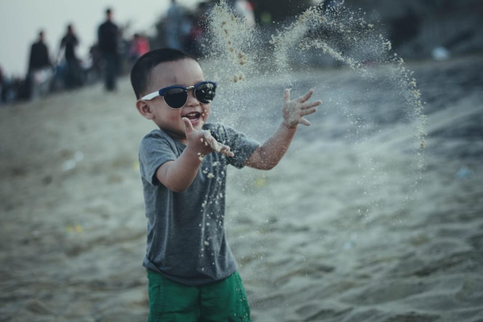 Boy wearing sunglasses playing in the sand